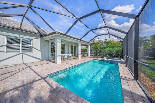 view of pool with a patio, glass enclosure, a pool with connected hot tub, and a ceiling fan