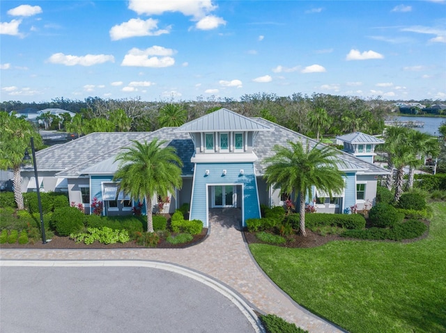 view of front of house featuring driveway, a standing seam roof, metal roof, and a front lawn