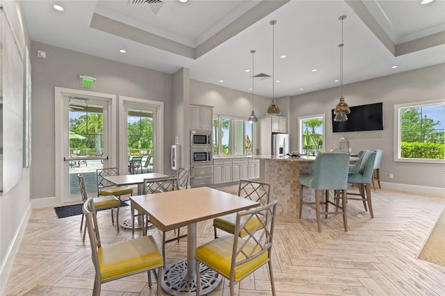 dining area with a raised ceiling, visible vents, plenty of natural light, and baseboards