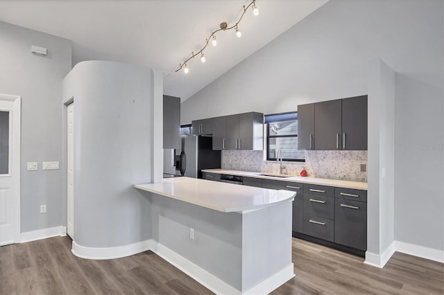 kitchen with decorative backsplash, stainless steel fridge with ice dispenser, wood finished floors, light countertops, and a sink