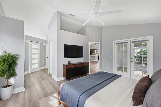 bedroom featuring a barn door, wood finished floors, vaulted ceiling, access to outside, and french doors