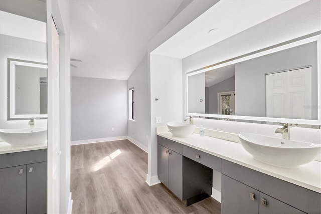 bathroom featuring lofted ceiling, a sink, and wood finished floors