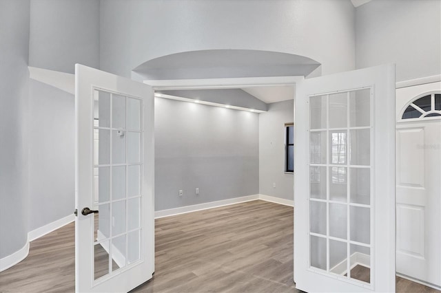 spare room featuring french doors, wood finished floors, and baseboards