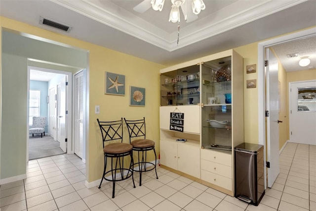 interior space featuring ornamental molding, a raised ceiling, visible vents, and light tile patterned floors