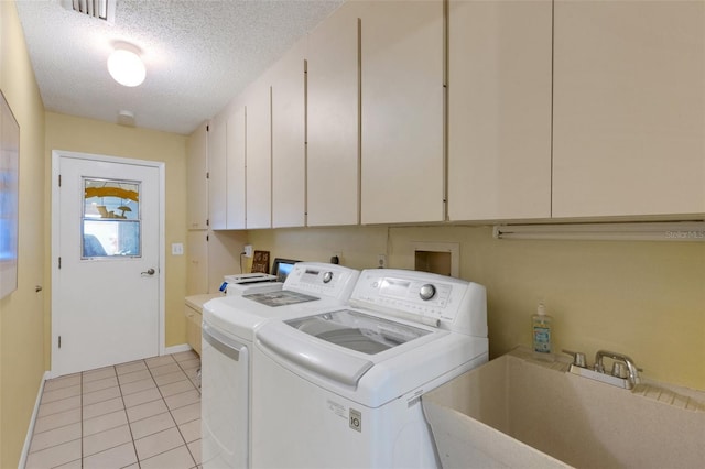 clothes washing area featuring light tile patterned floors, a textured ceiling, a sink, cabinet space, and washing machine and clothes dryer