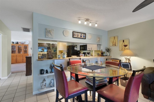 dining area featuring visible vents, a textured ceiling, and light tile patterned flooring