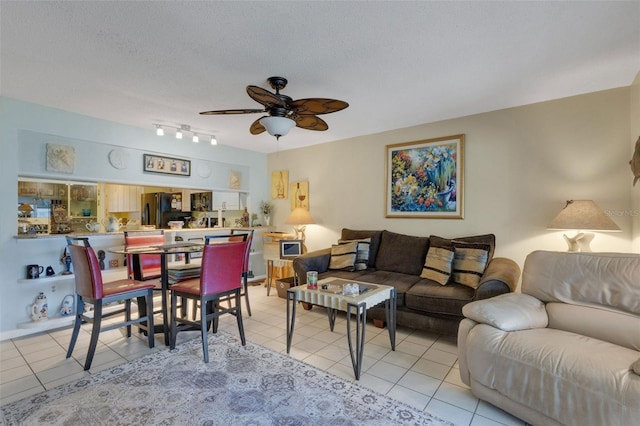 living area with a ceiling fan, a textured ceiling, and light tile patterned flooring