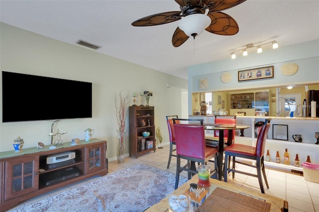 tiled dining area featuring a textured ceiling, baseboards, visible vents, and a ceiling fan