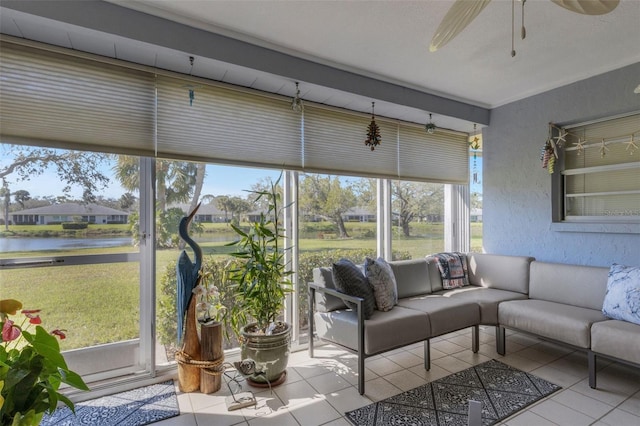 sunroom with a ceiling fan and a water view