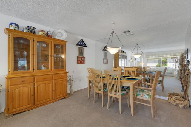 dining space featuring a textured ceiling, visible vents, and light colored carpet