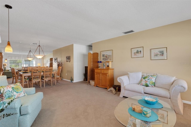 living area featuring baseboards, visible vents, light carpet, and a textured ceiling