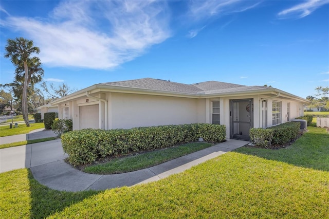 ranch-style home with an attached garage, a shingled roof, concrete driveway, stucco siding, and a front yard