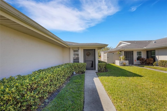 entrance to property with a lawn and stucco siding