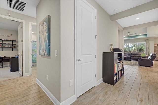 hall with baseboards, visible vents, and light wood-style floors