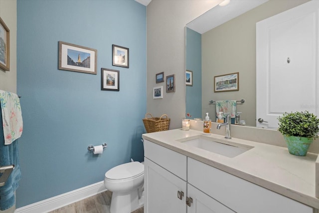 bathroom featuring wood finished floors, vanity, toilet, and baseboards