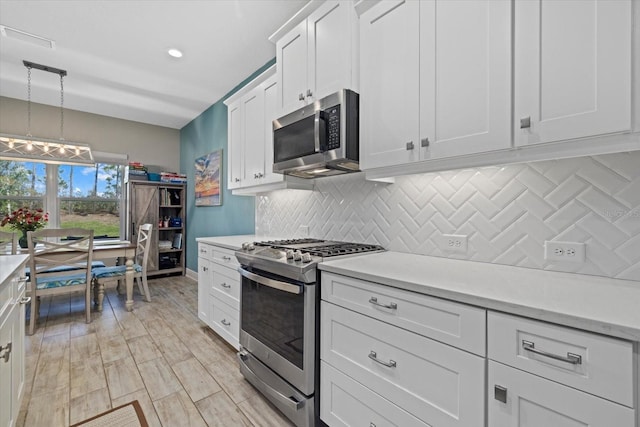 kitchen featuring light countertops, hanging light fixtures, backsplash, appliances with stainless steel finishes, and white cabinets