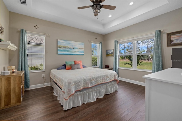 bedroom featuring visible vents, baseboards, a raised ceiling, and dark wood-style flooring