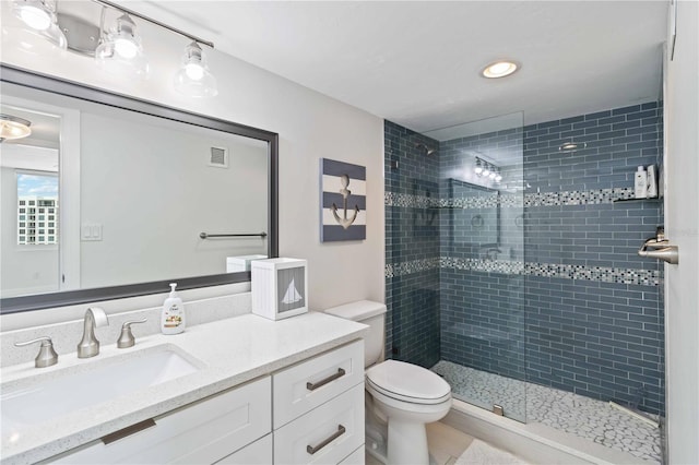 bathroom with toilet, vanity, a tile shower, and visible vents