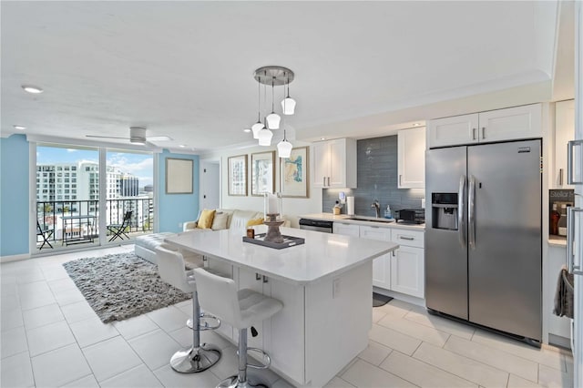 kitchen with appliances with stainless steel finishes, open floor plan, backsplash, expansive windows, and a sink