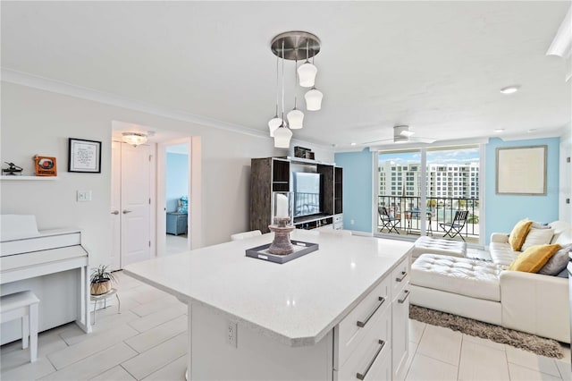 kitchen featuring white cabinets, open floor plan, hanging light fixtures, ornamental molding, and a center island