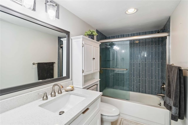 full bath with enclosed tub / shower combo, vanity, and toilet