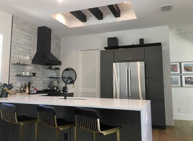 kitchen with open shelves, light countertops, visible vents, freestanding refrigerator, and wall chimney exhaust hood