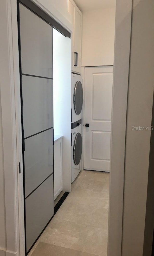 washroom featuring stacked washer and dryer and cabinet space