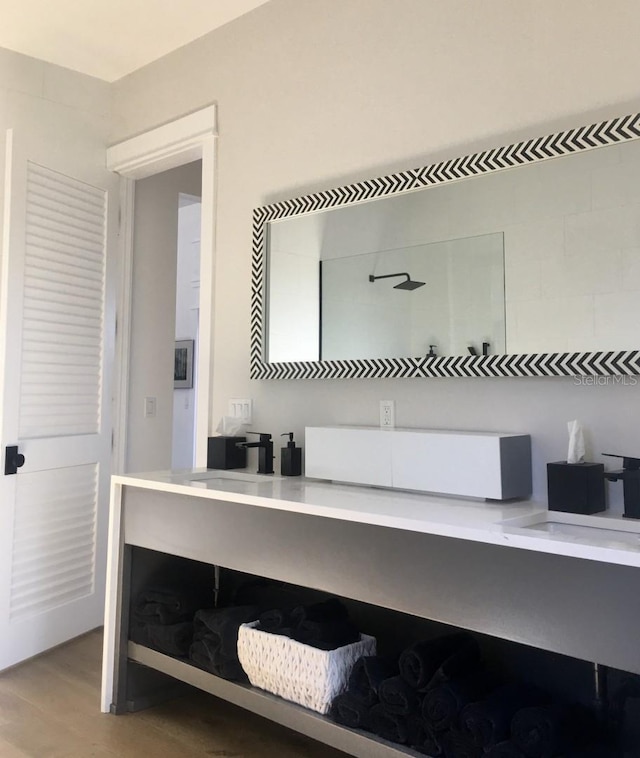 bathroom with double vanity, wood finished floors, and tiled shower