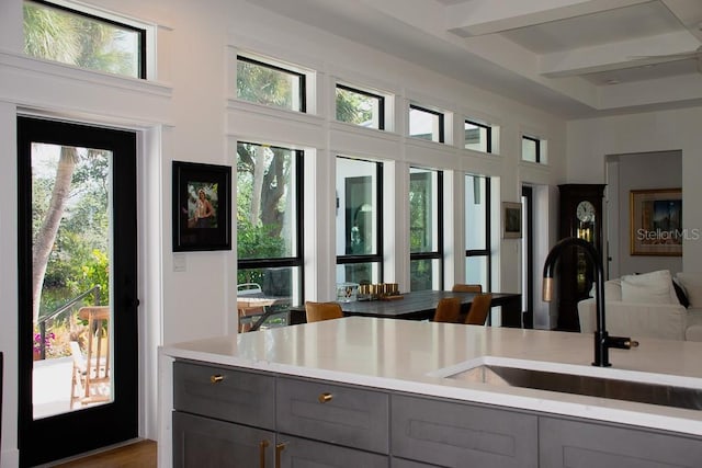 interior space with a sink, light countertops, open floor plan, and gray cabinets