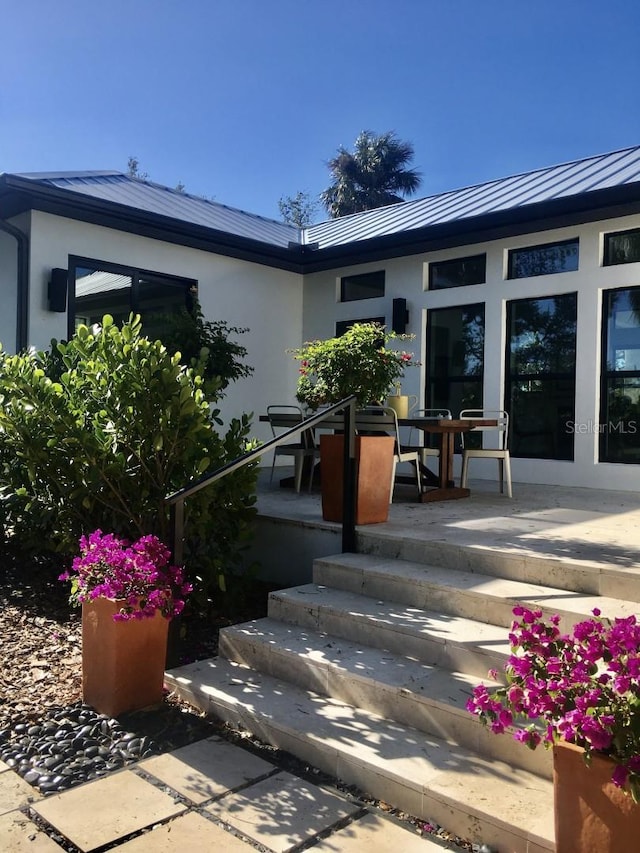 view of exterior entry featuring metal roof, a standing seam roof, and stucco siding