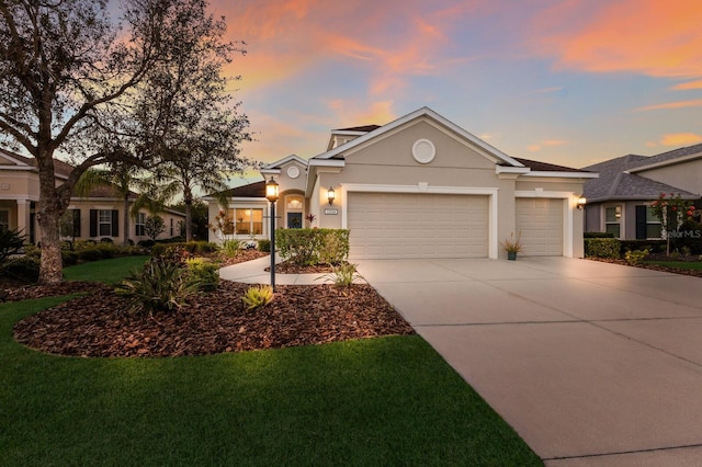 view of front facade with a yard, an attached garage, driveway, and stucco siding