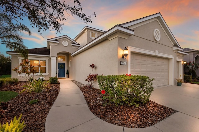 view of front of property featuring a garage, concrete driveway, and stucco siding