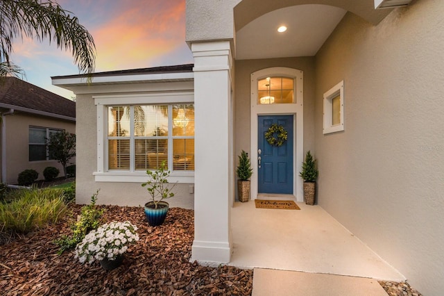 exterior entry at dusk featuring stucco siding