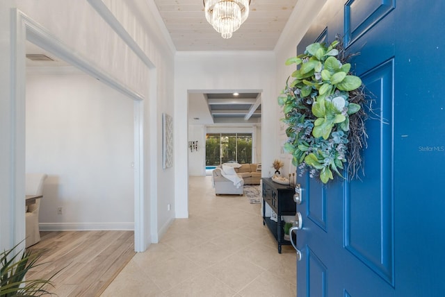 entrance foyer with visible vents, ornamental molding, wood ceiling, a chandelier, and baseboards