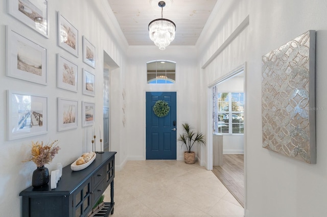 foyer entrance featuring light tile patterned floors, a notable chandelier, baseboards, and crown molding