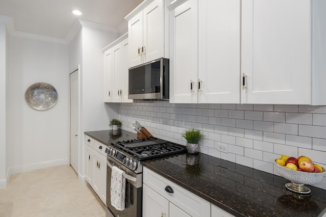 kitchen with stainless steel appliances, white cabinets, baseboards, ornamental molding, and dark stone countertops