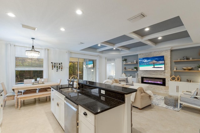 kitchen with built in shelves, a center island with sink, a wealth of natural light, stainless steel dishwasher, and a sink