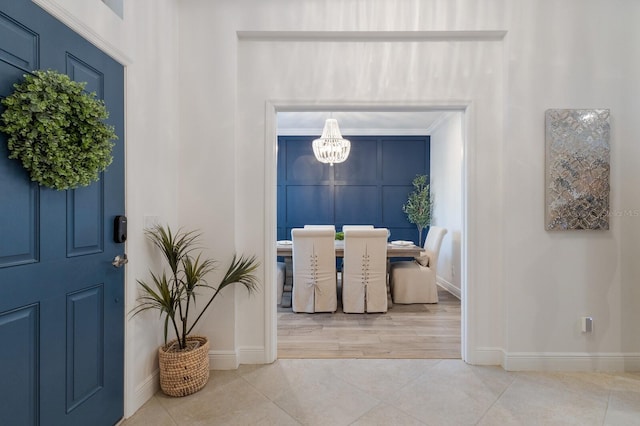 tiled foyer with baseboards and an inviting chandelier