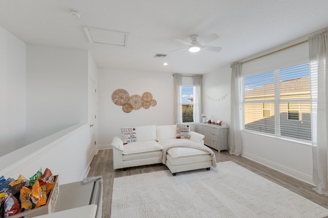 living area featuring baseboards, wood finished floors, visible vents, and attic access