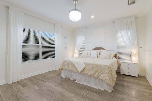 bedroom featuring multiple windows, visible vents, baseboards, and wood finished floors