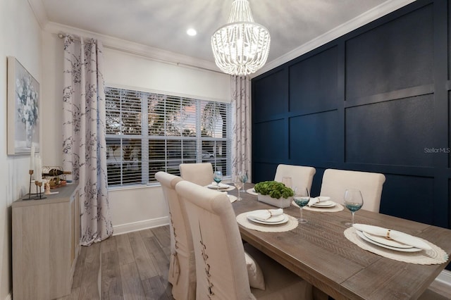 dining room with baseboards, ornamental molding, wood finished floors, an inviting chandelier, and a decorative wall