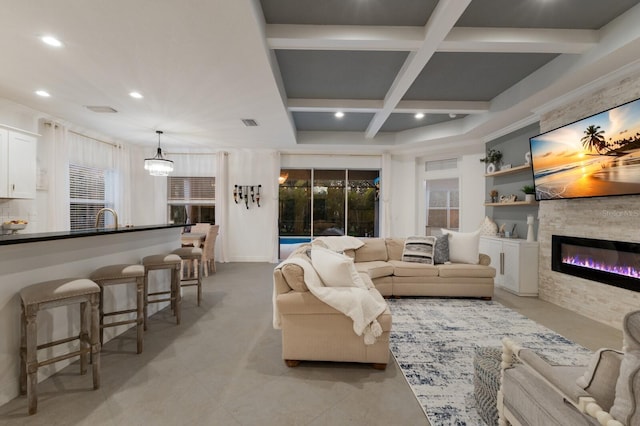 living area with a stone fireplace, beamed ceiling, coffered ceiling, and visible vents