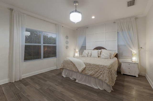 bedroom featuring ornamental molding, visible vents, baseboards, and wood finished floors