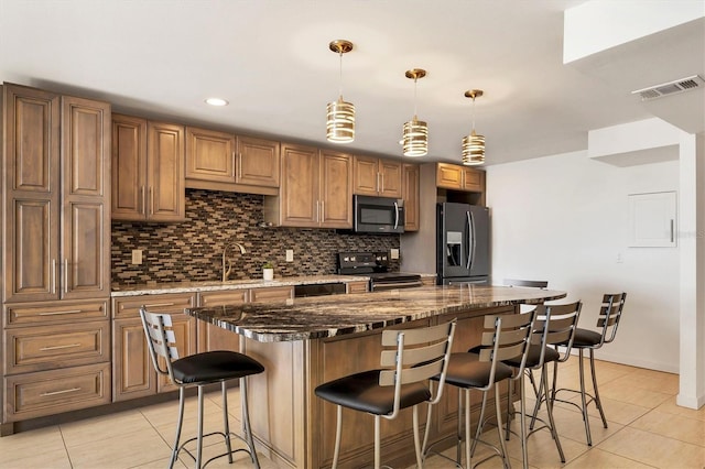 kitchen with visible vents, decorative backsplash, appliances with stainless steel finishes, a breakfast bar, and a sink