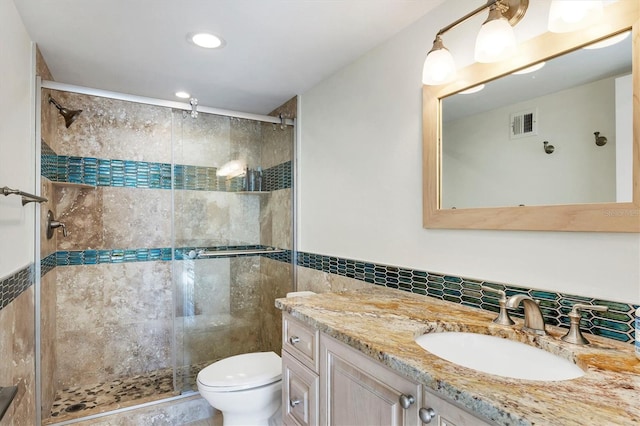 bathroom with tile walls, visible vents, toilet, a shower stall, and vanity