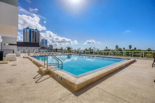 pool with a patio area and a city view