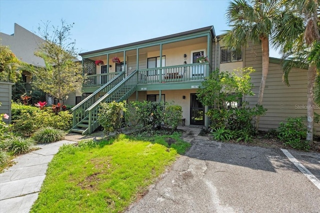 view of front of home featuring a porch, stairway, and stucco siding