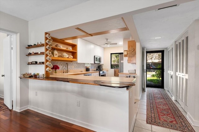 kitchen featuring stainless steel appliances, a sink, light wood-style floors, open shelves, and tasteful backsplash