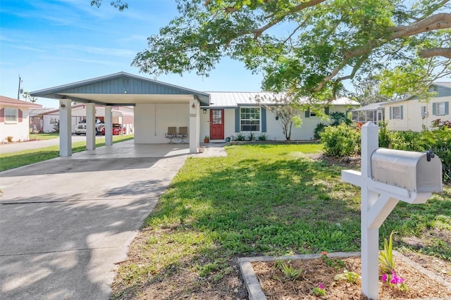 view of front of house with driveway, metal roof, a carport, and a front yard