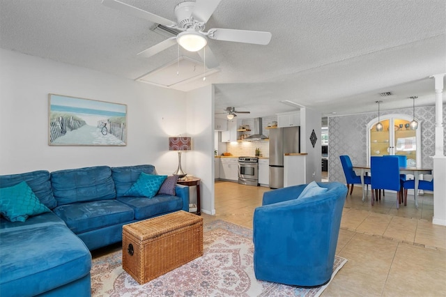 living area featuring light tile patterned floors, a textured ceiling, attic access, and baseboards